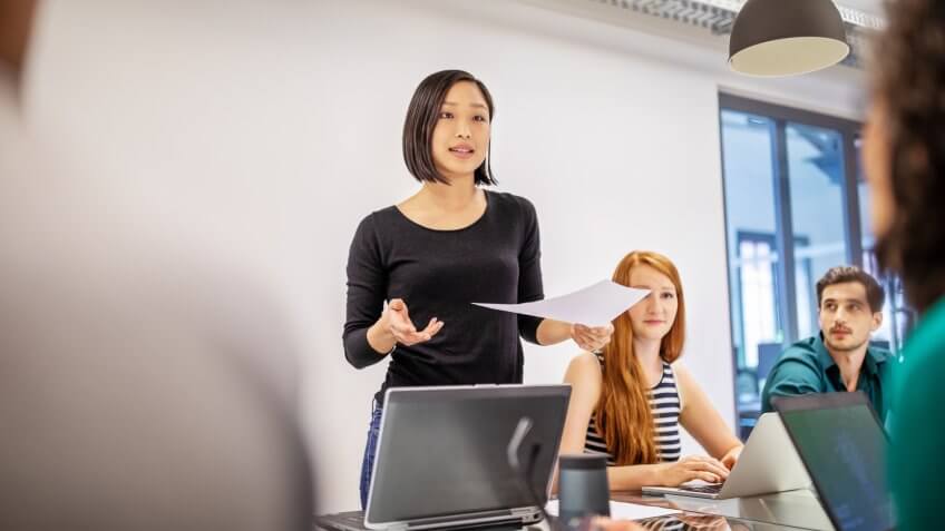 Confident female professional discussing in board room.