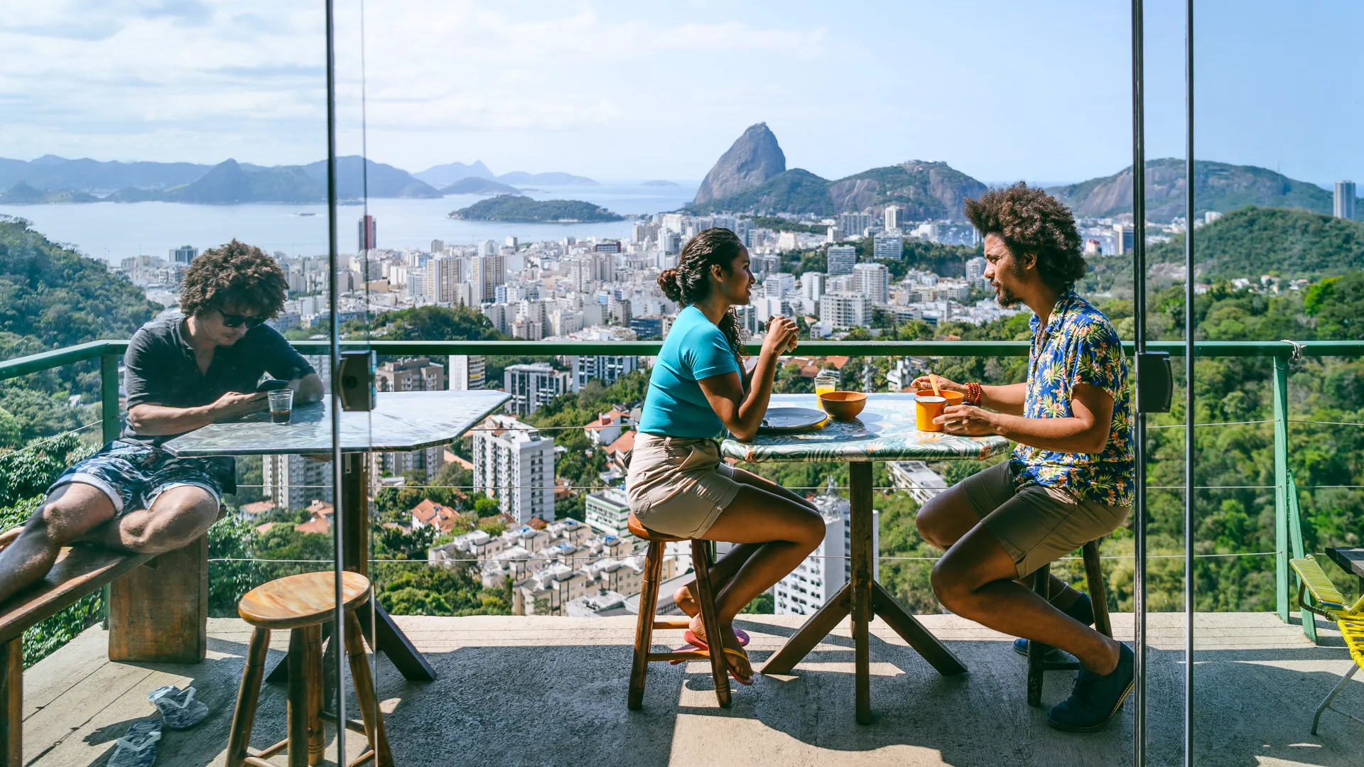 Man and woman on balcony, scenic view and city backdrop, on vacation.