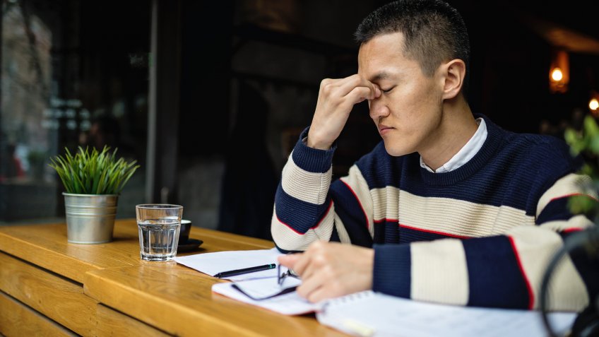 Succesful young japanese freelance worker organizing his time while sitting in a cafe.