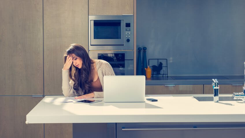 Woman doing paperwork with a laptop and digital tablet.