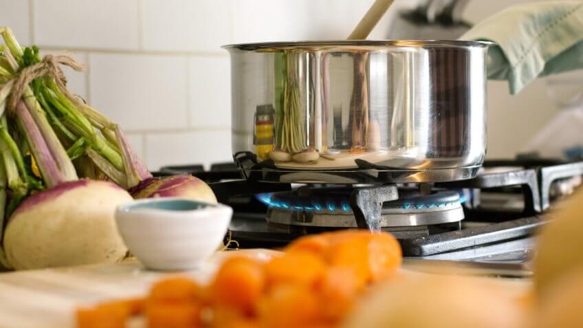 Cropped shot of woman stirring food in the cooking pan in kitchen.
