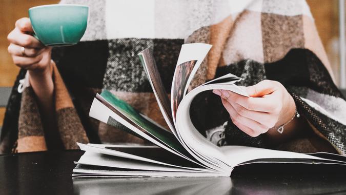 Reading magazine and drinking coffee Girl are sitting in the coffee shop with cup of coffee and reading book or magazine.