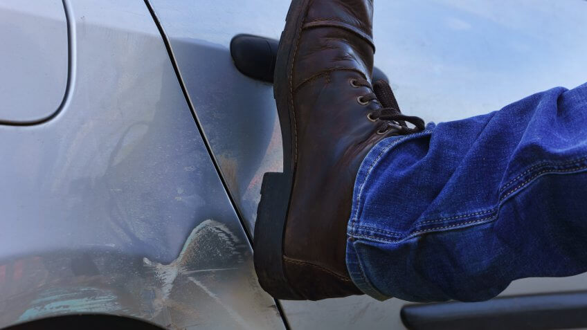 guy kicking car door shut