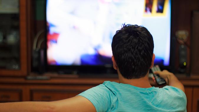Male watching television in home living room / channel hopping Male watching television in home living room / channel hopping.
