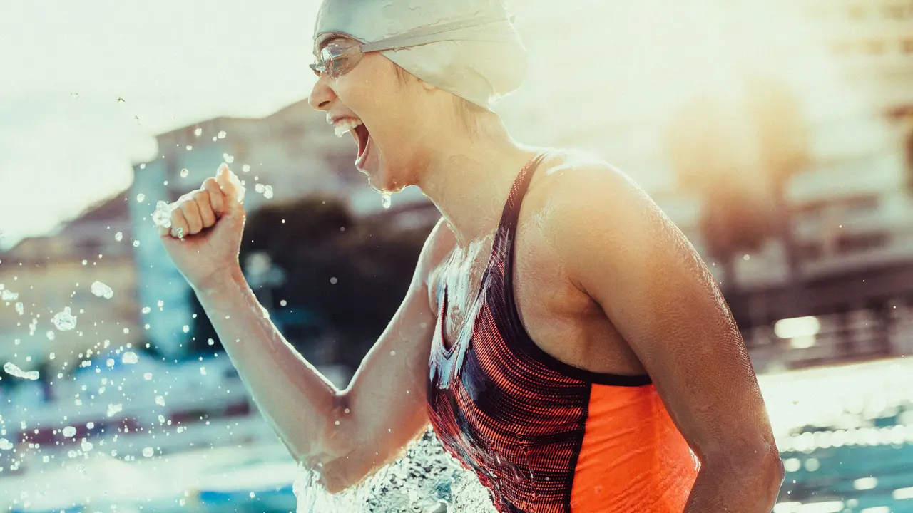high performance female swimmer with clenched fist celebrating victory in the swimming pool.