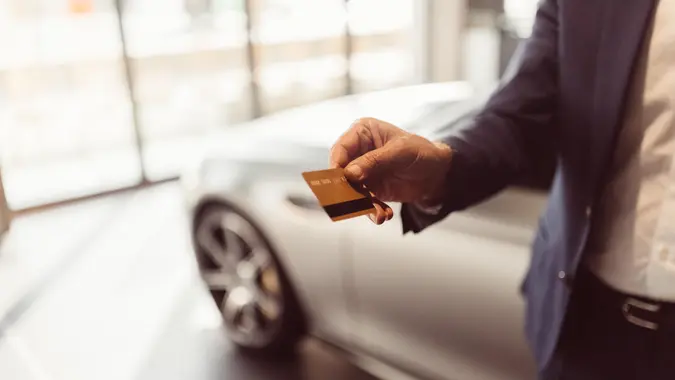 Businessman buying a new car with credit card.