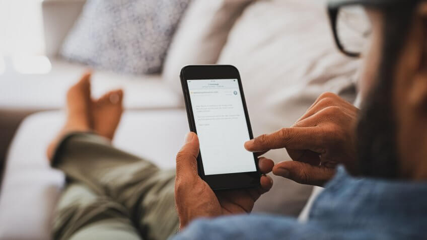 Closeup of a man hand holding cellphone with internet browser on screen.