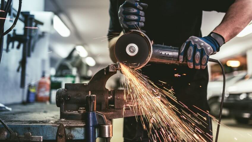 Heavy industry worker cutting steel with an angle grinder.