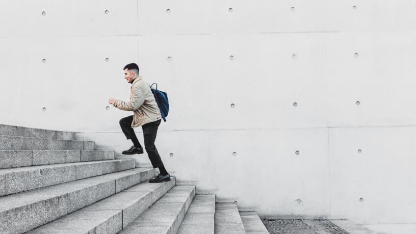 Young man running up steps in urban setting.