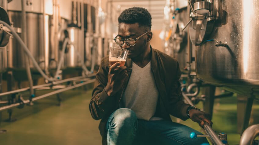 Brew master testing beer in brewery.