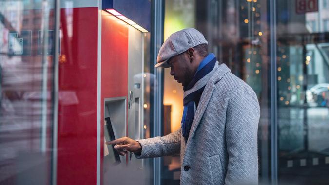 African businessman on a ATM machine Handsome and beautiful black businessman using a ATM machine in the city.