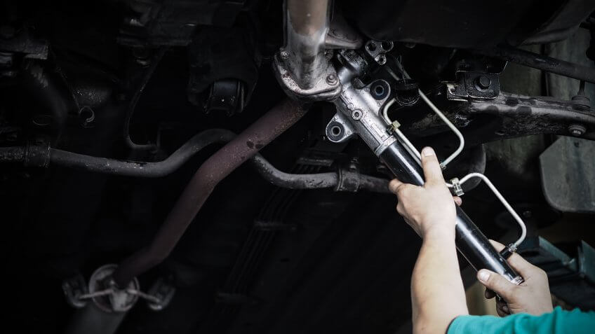 mechanic changing steering rack on vehicle