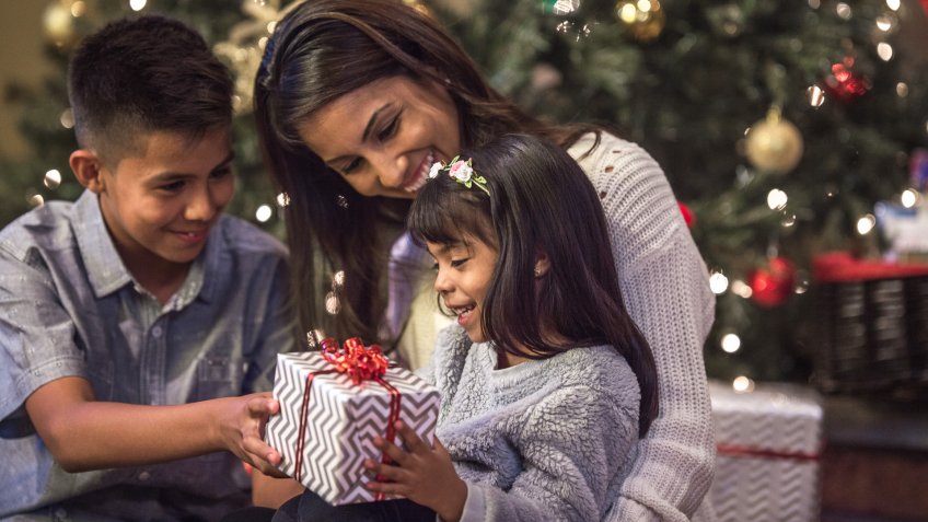 A brother is giving his sister a present on Christmas morning.