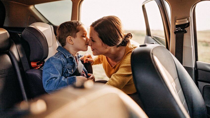 Pregnant mother preparing his son for travel in car.