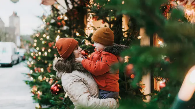 Caucasian mother with preschool son standing near Christmas tree in Rothenburg.