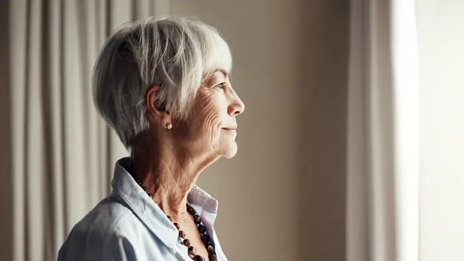 Cropped shot of a senior woman looking out the window at home.