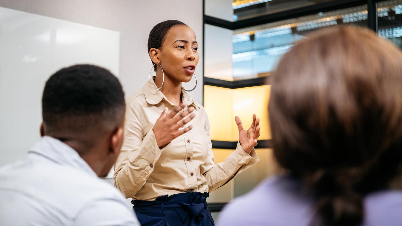 Passionate young woman in her 20s with short hair, discussing with colleagues, African female manger leading her team, ambition, aspiration, empowerment.