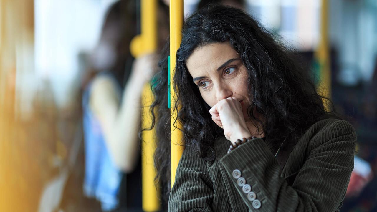 Pensive young woman traveling with bus and holding smart phone.