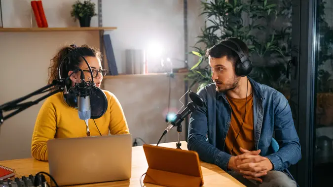 Photo of two young people recording a podcast in a studio.