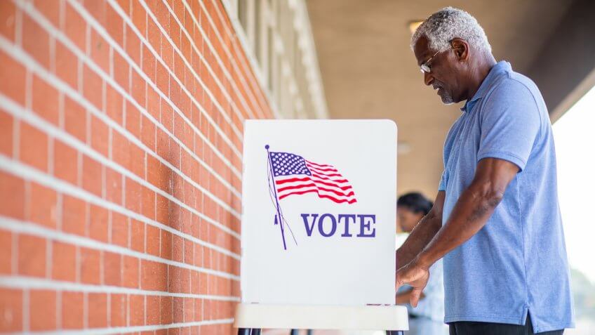 A senior black man casts his ballot on election day.