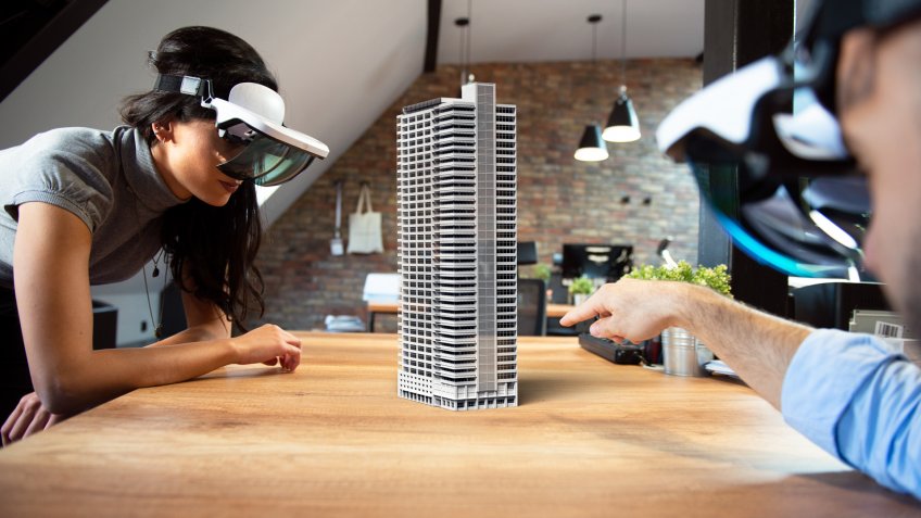 Two people working on virtual 3d building by using AR glasses.