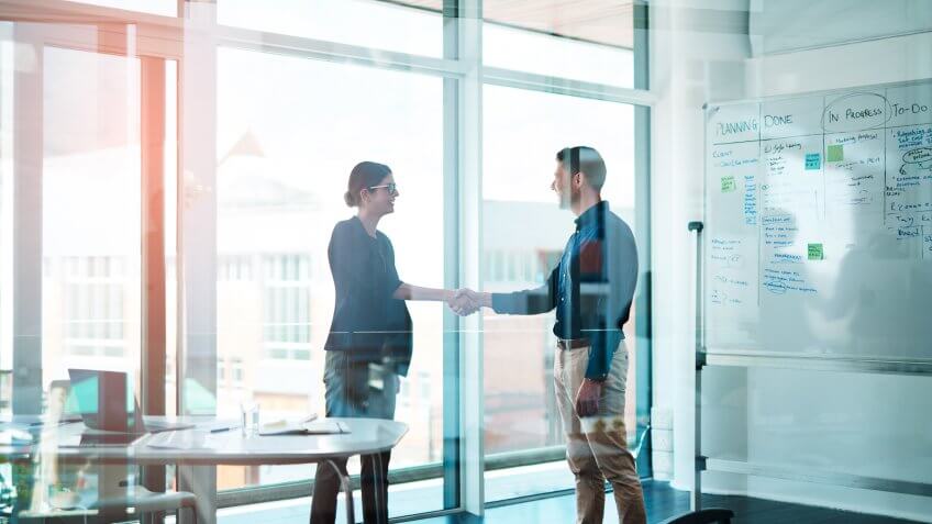 Shot of a businessman and businesswoman shaking hands in a modern office.