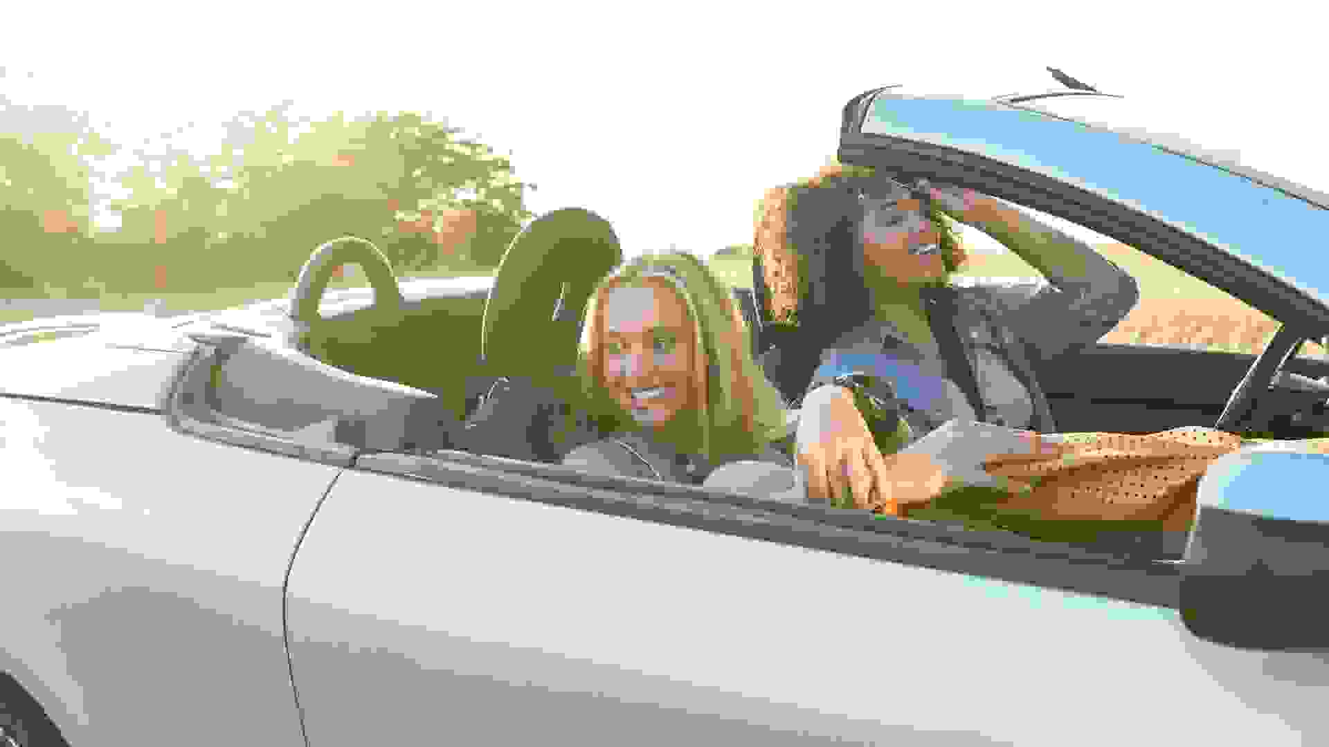 Two beautiful women traveling with a car, laughing ang having fun.
