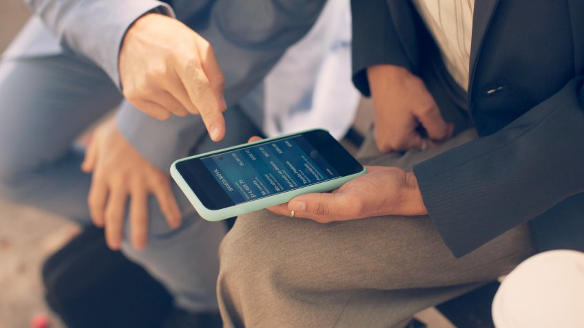 Business people talking about mobile banking outdoors.
