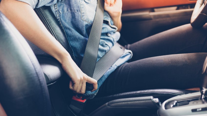 Asian woman fastening seat belt in the car, safety concept.