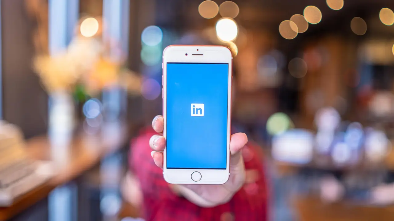 woman holding up smartphone with LinkedIn app