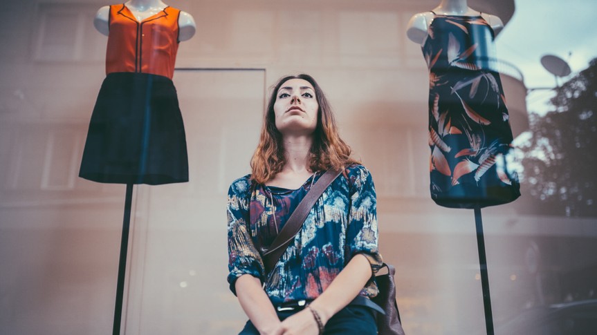 Unhappy young woman standing in front of the clothing store.