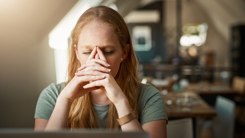 Cropped shot of a young woman looking stressed while sitting in front of her laptop.
