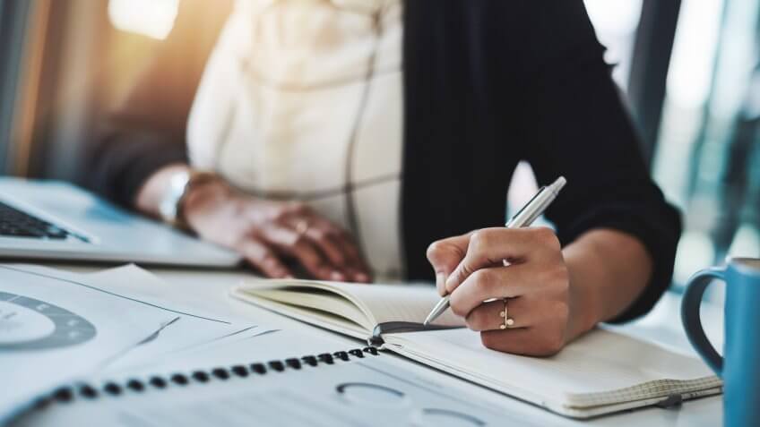 Cropped shot of a businesswoman making notes at her desk in a modern office.