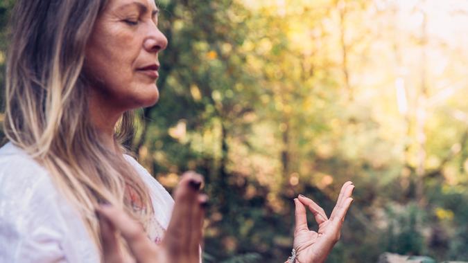 Mature Woman Meditating in Forest.