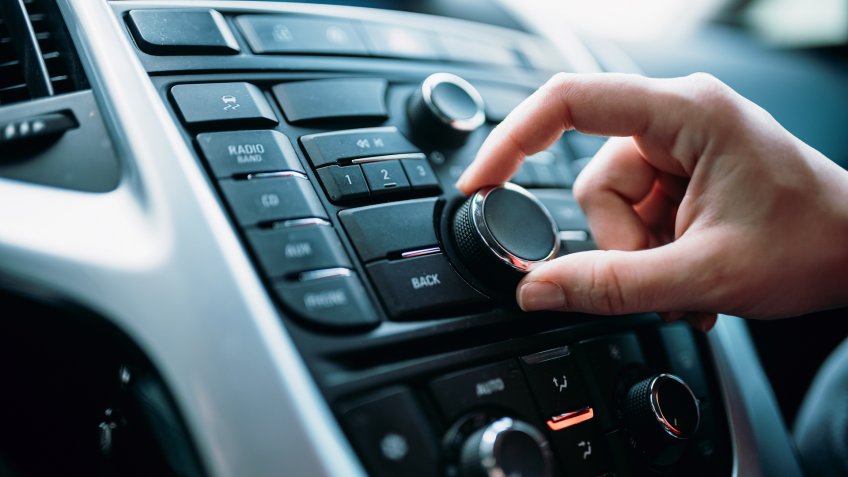 Closeup of young woman hand control radio volume.