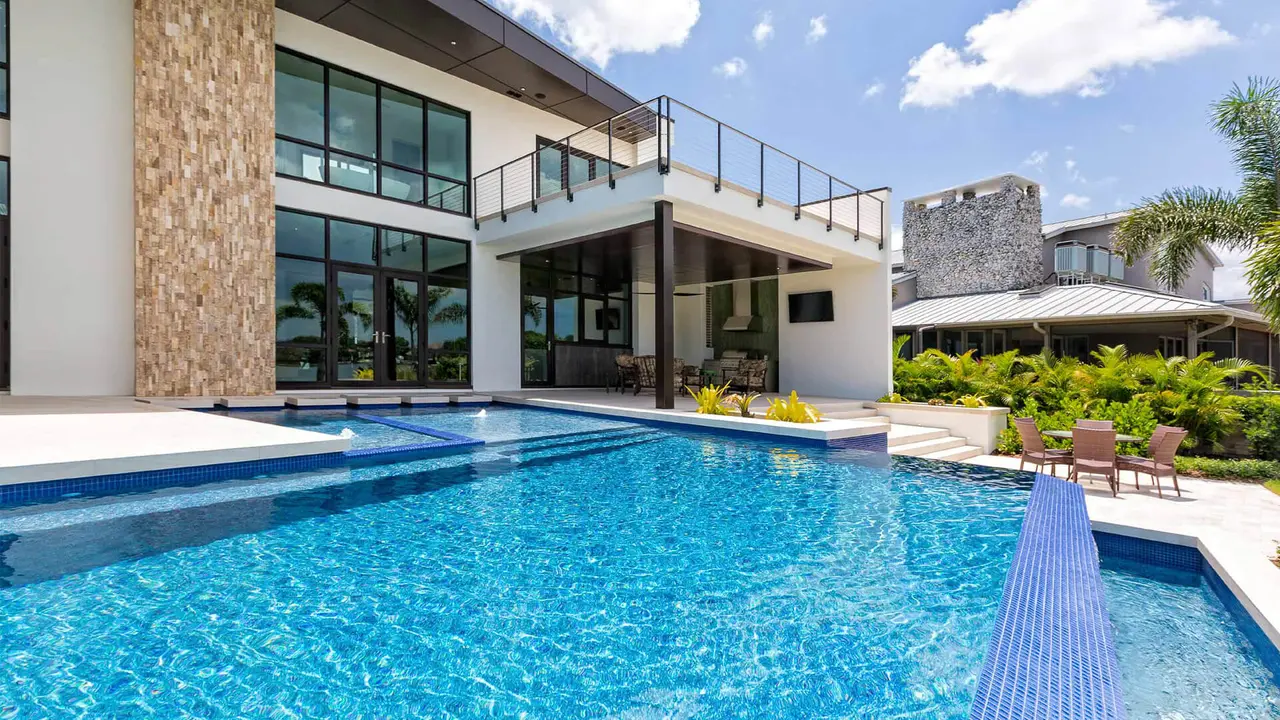 A luxury house with a sparkling blue swimming pool in the backyard on a sunny day.
