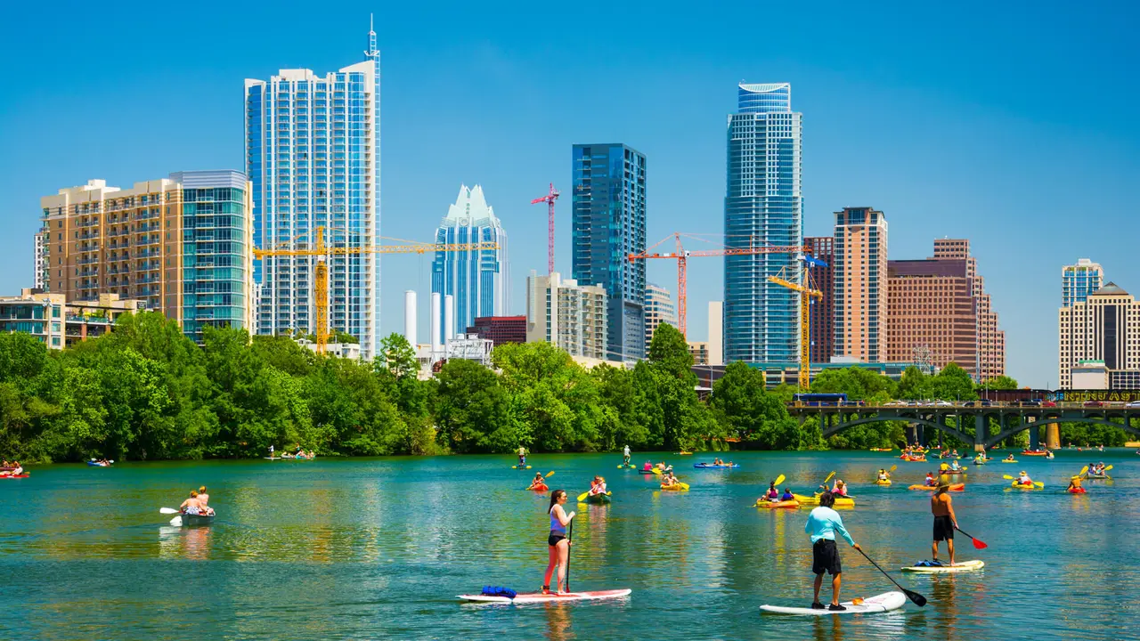 Austin, United States - May 3, 2014: People having fun on rowboats and boards in Lady Bird Lake on a nice day with the Austin skyline in the background.