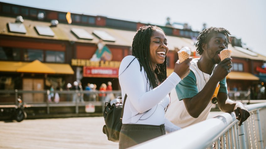 A cute young man and woman enjoy a tasty ice cream waffle cone on a sunny day in downtown Seattle.