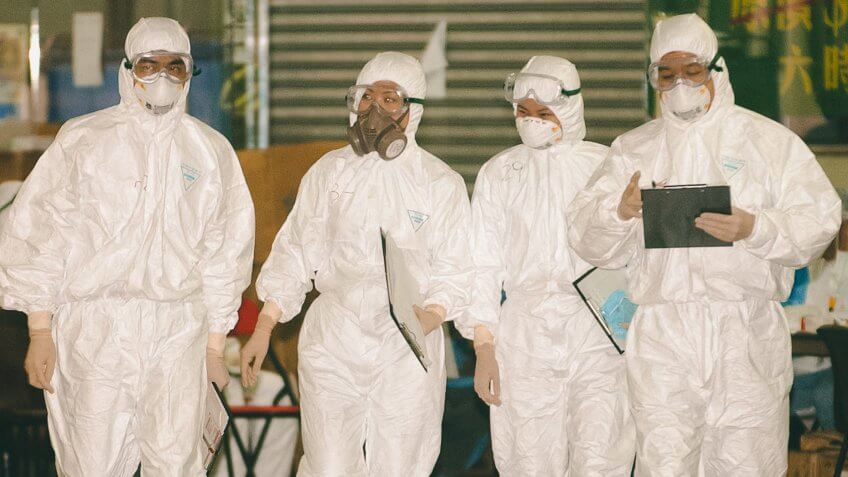 GEAR Health Officials in cover-all protective gear against a mysterious flu-like illness walk outside Hong Kong's Amoy Gardens .