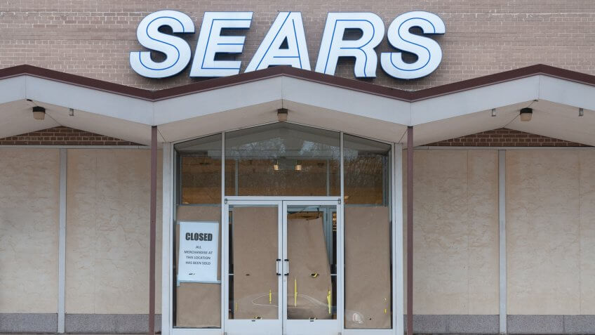 Michigan City, Indiana / USA - March 24 2019: an empty Sears store sits shuttered in an empty parking lot with closed sign and paper covering the glass doors.
