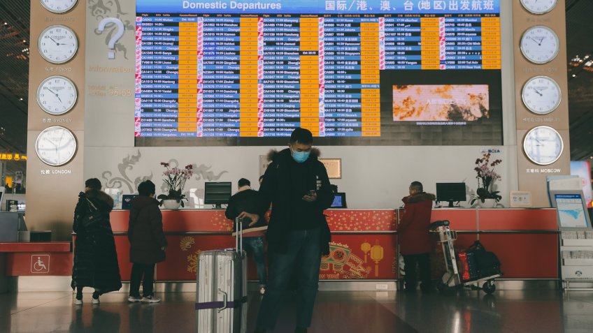 A passenger wears mask standing in front of a departure information screen at terminal 3 of Beijing Capital International Airport in Beijing, China, 26 January 2020.