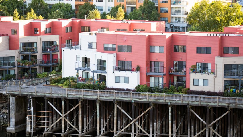 Painted three-story residential apartments with flat roof built on wooden stilts on the banks of the Willamette River in downtown Portland "u2013 nice place to living in popular waterfront area.