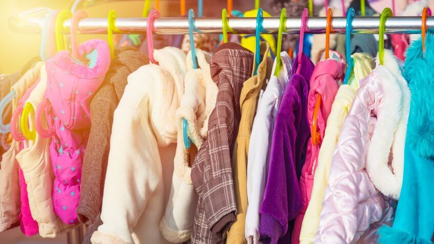 Rack of baby and children jackets displayed at outdoor hanger market for sale.