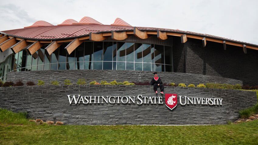 May 6, 2018 Young male student in gown uniform sitting for picture taking, WA, USA.