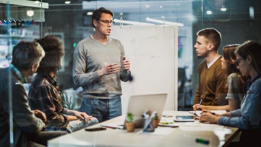 Mid adult manager talking while having presentation with his team in the office.