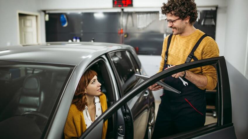 Repairman solving the car problems with a female customer in the car workshop.