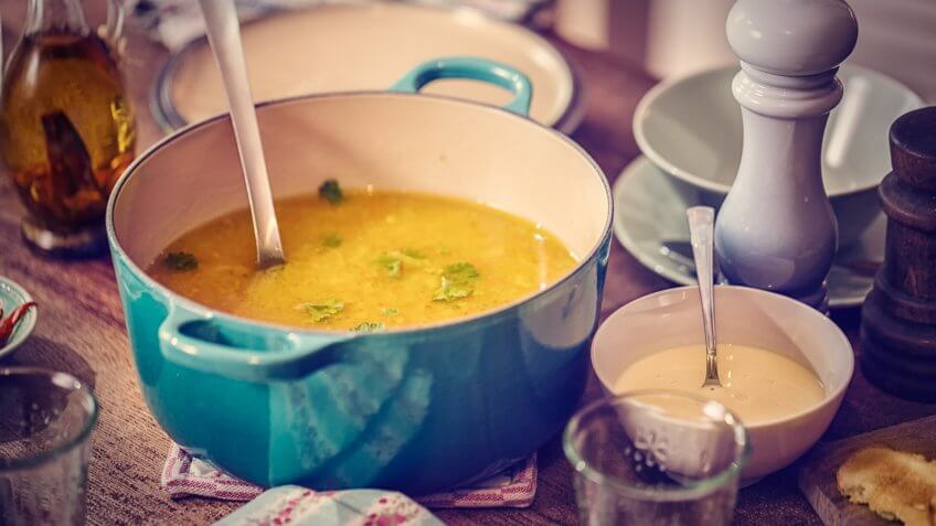 Little girl eating delicious chicken soup with carrots, onions and parsnips.