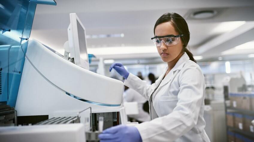 Shot of a young woman using a machine to conduct a medical test in a laboratory.