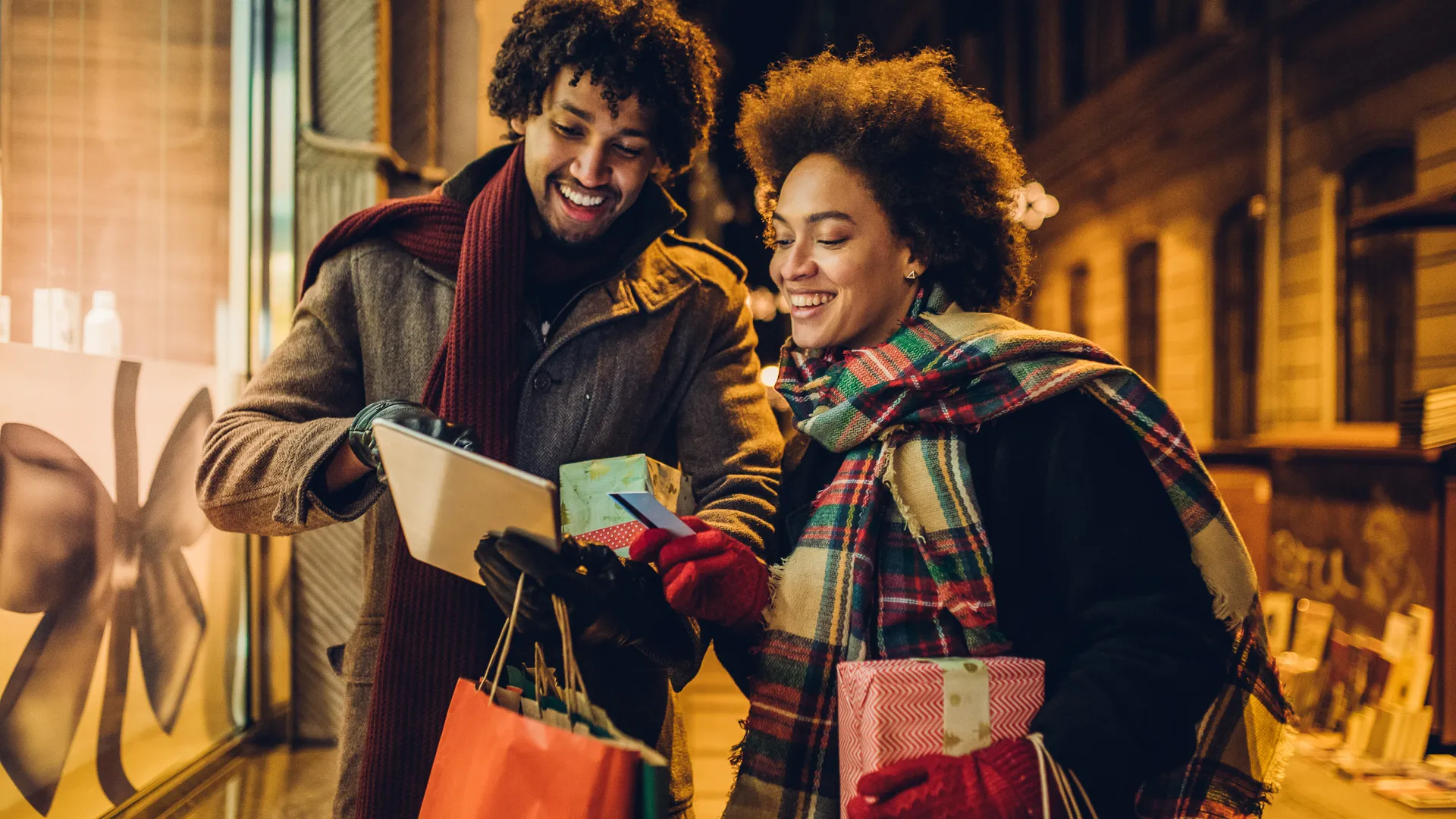 微笑的年轻夫妇购买圣诞礼物在线使用信用卡和数字平板电脑。