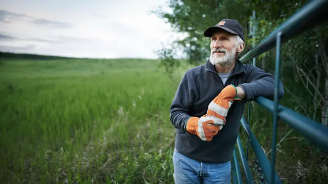 Shot of a mature man standing at the fence of a farm.